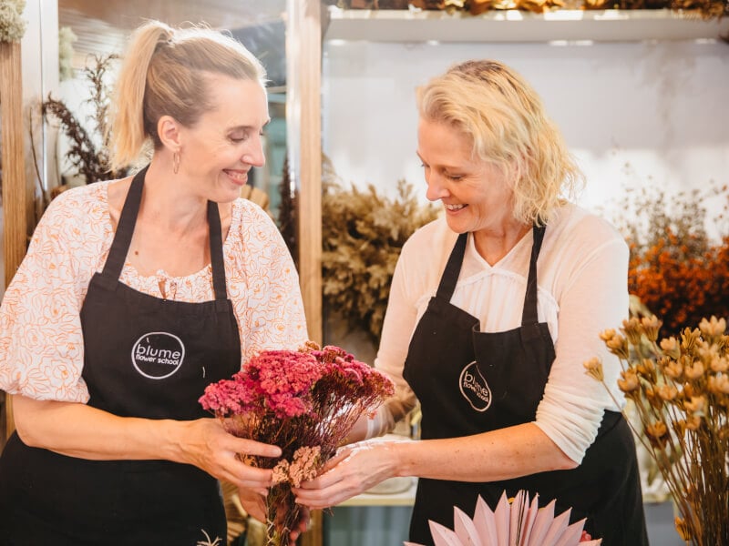 Two women displaying their bouquets at a flower arranging class